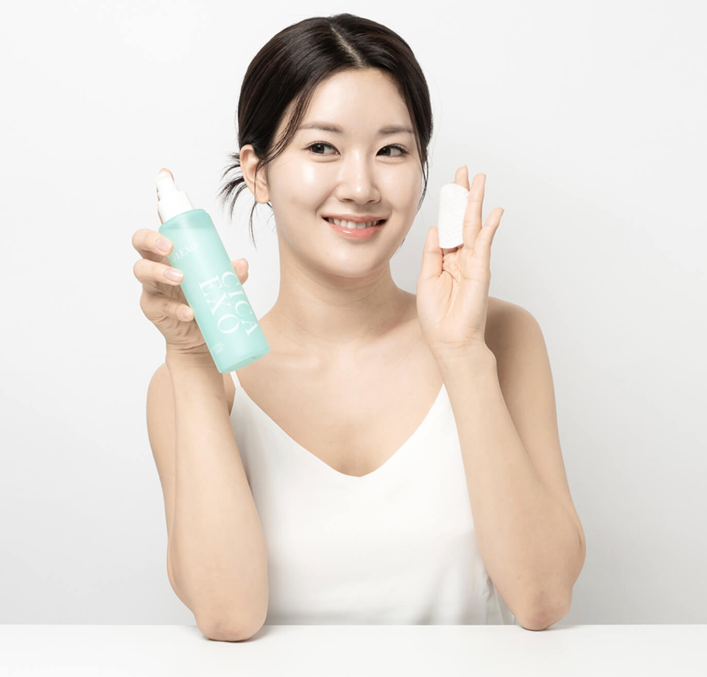 D'LEXO CICA EXO COMFORTING Toner. Woman holding a green bottle and a white cap against a white background