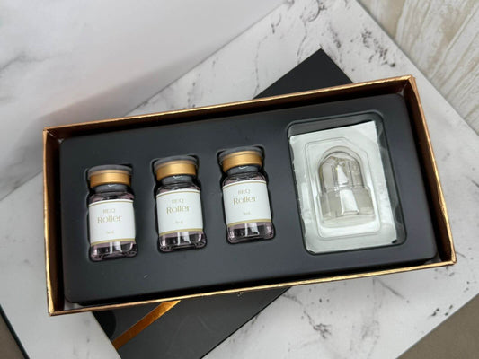 Set of small glass bottles with gold caps in a black box on a marble surface