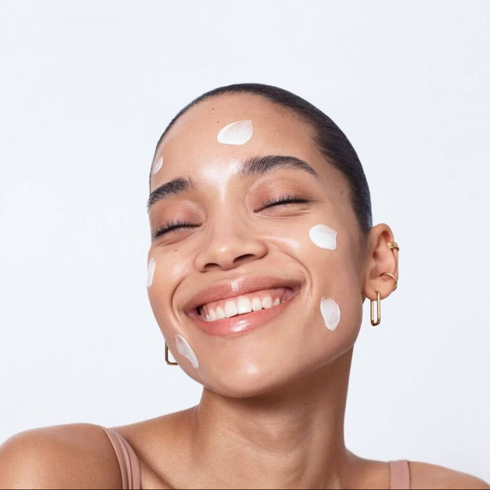 Woman with white patches on her face against a light gray background